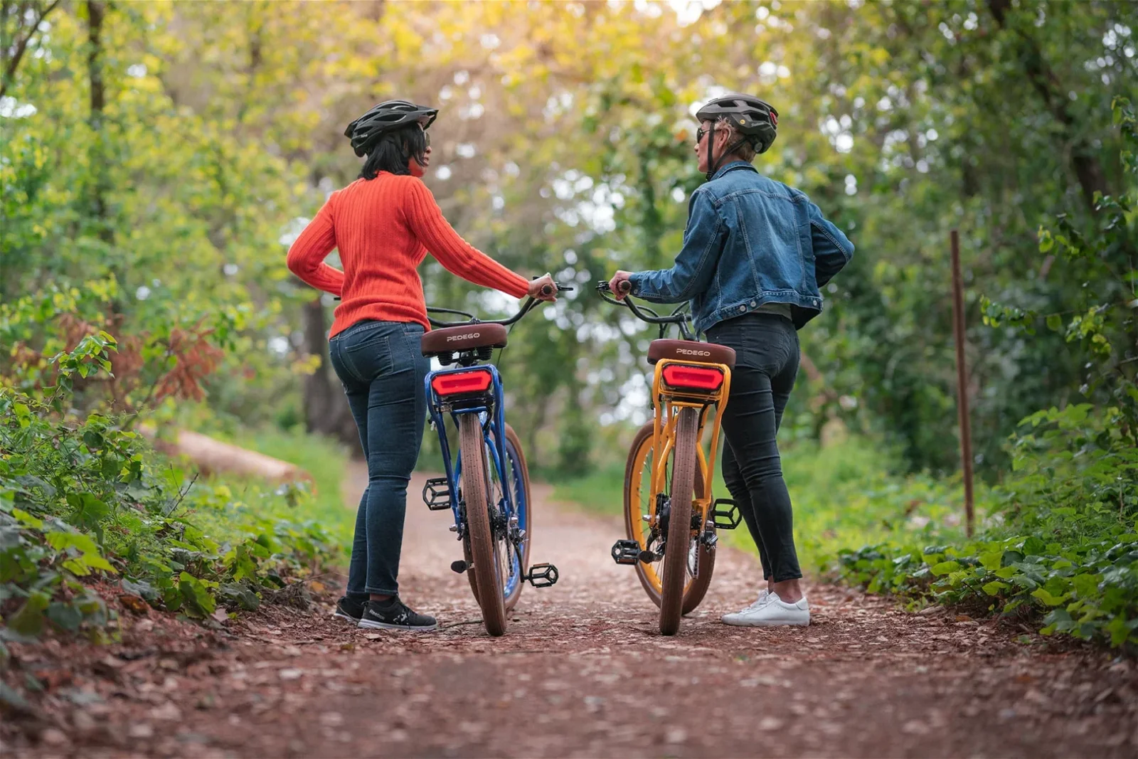 two bike riders walking with their Pedego electric bikes in a forest