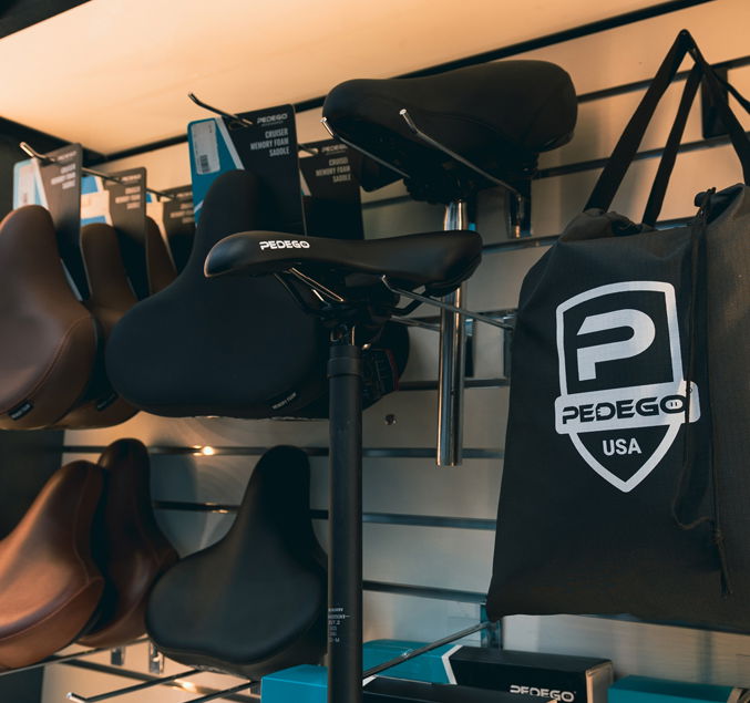 Pedego- A display of various bicycle seats and accessories organized on shelves, featuring the Pedego brand prominently.